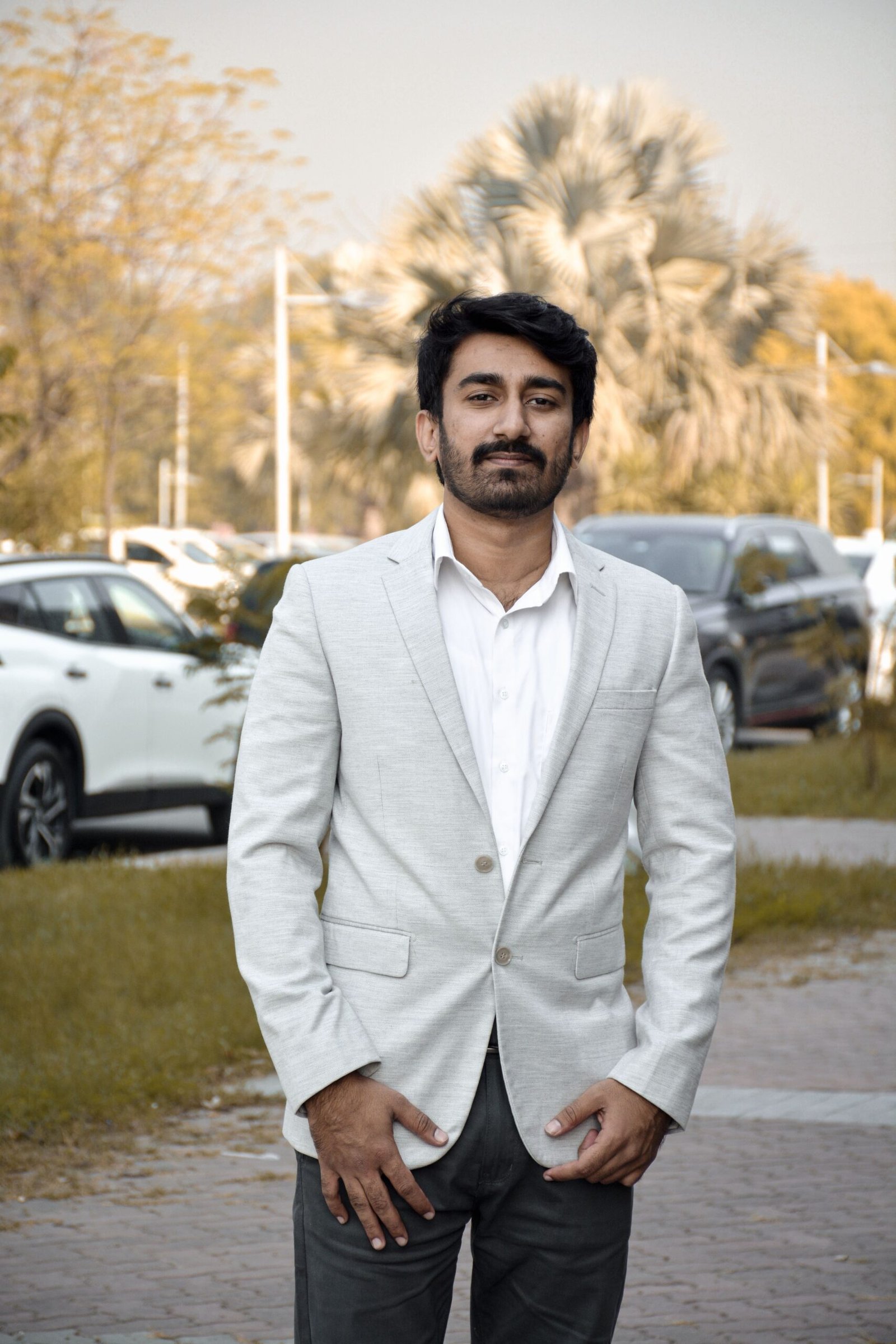 Elegant man in a white suit standing outdoors at a park in Islamabad, Pakistan.
